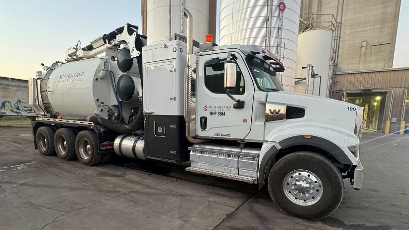 A large white truck parked in front of a silo.