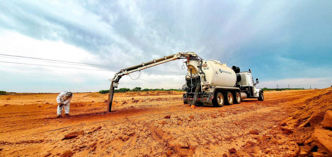 A cement truck is working on a dirt road.