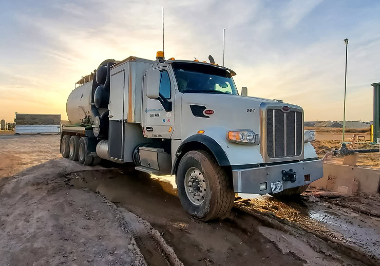 A large truck driving on a dirt road.