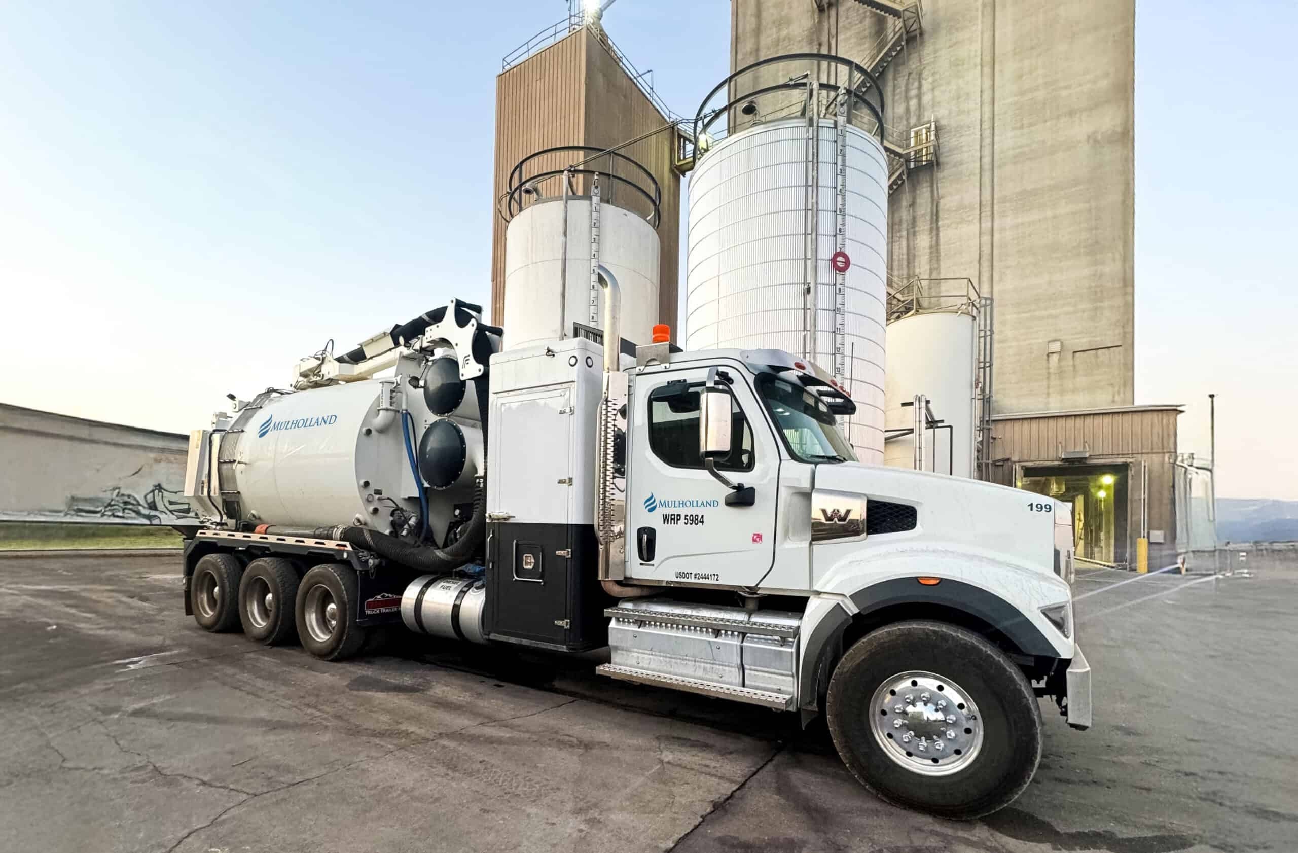 A large white truck parked in front of a silo.