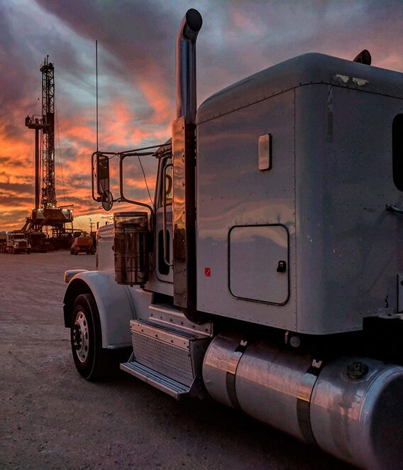 A semi truck parked in front of a drilling rig.