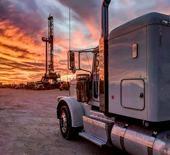A truck parked in front of a drilling rig.