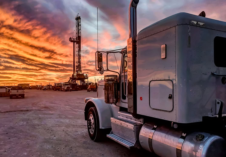 A truck parked in front of a drilling rig.