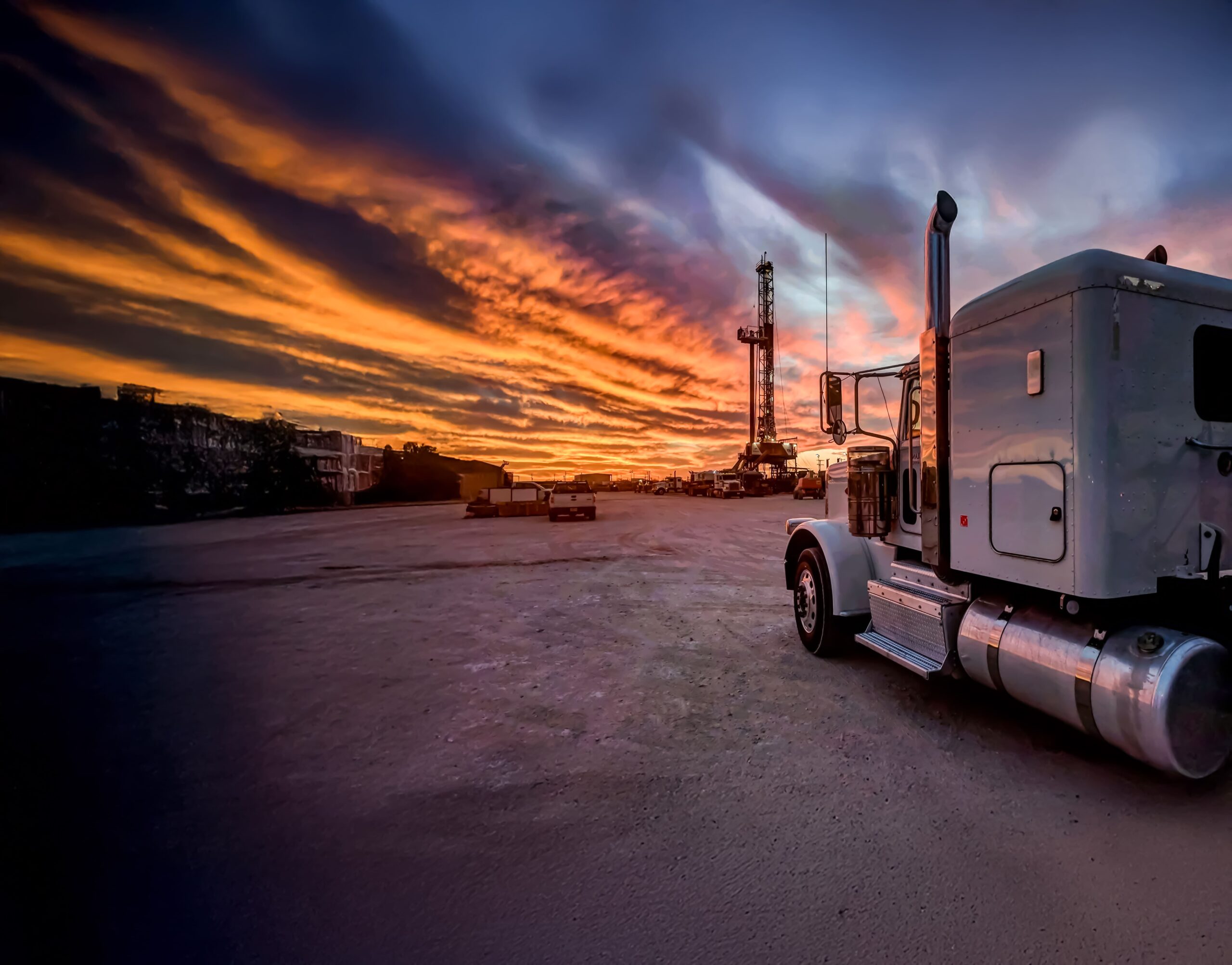 A semi truck parked in front of a sunset.
