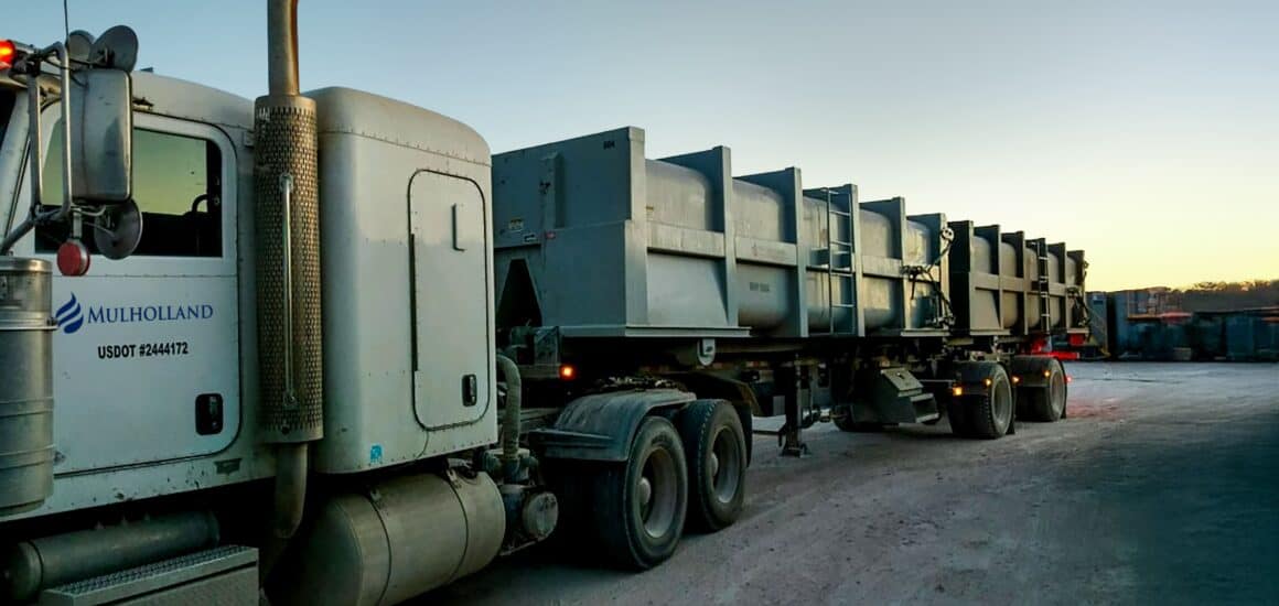 A large semi truck with a trailer parked in a lot.