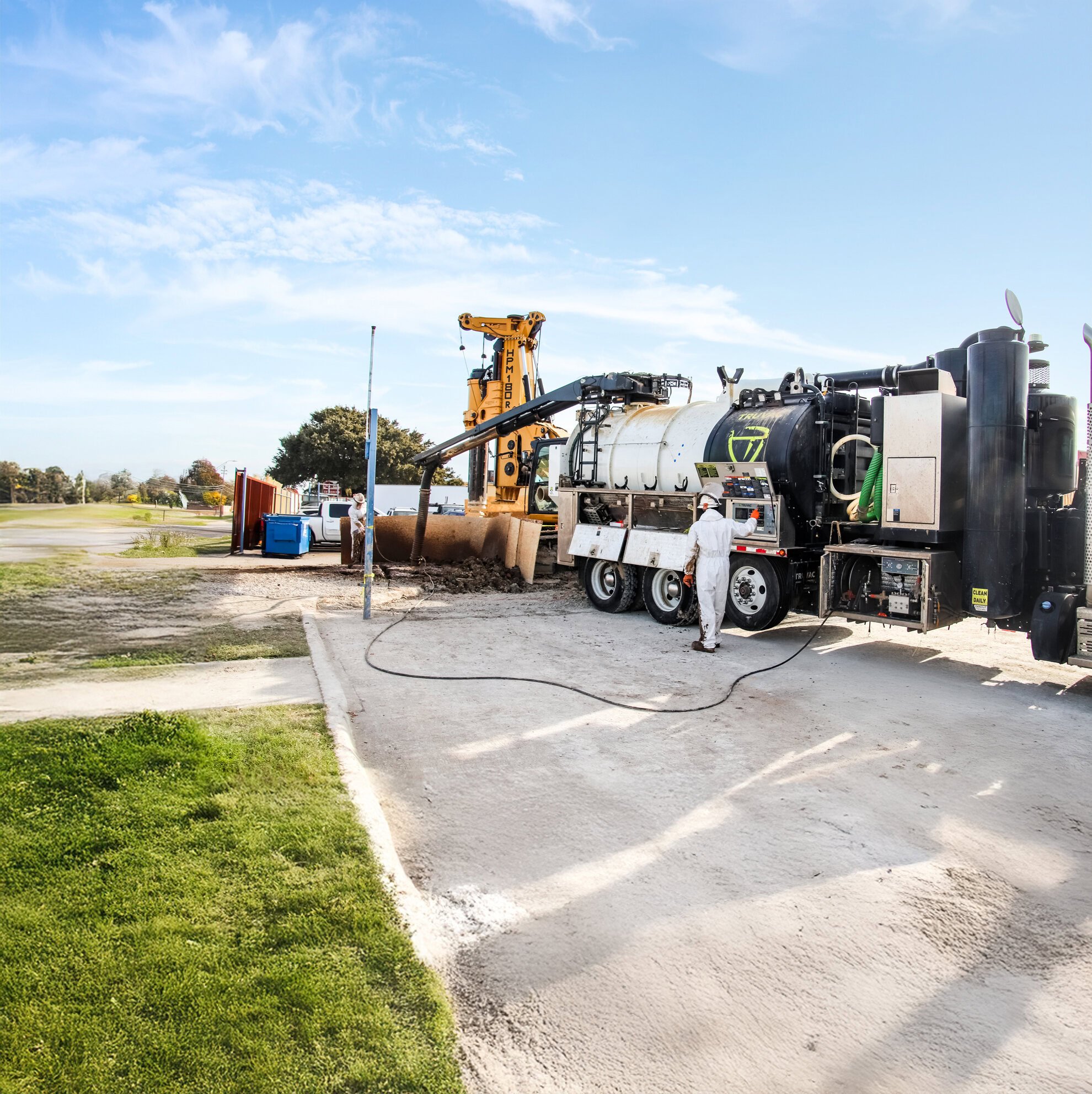 A man is standing next to a truck that is being used to clean up a field.