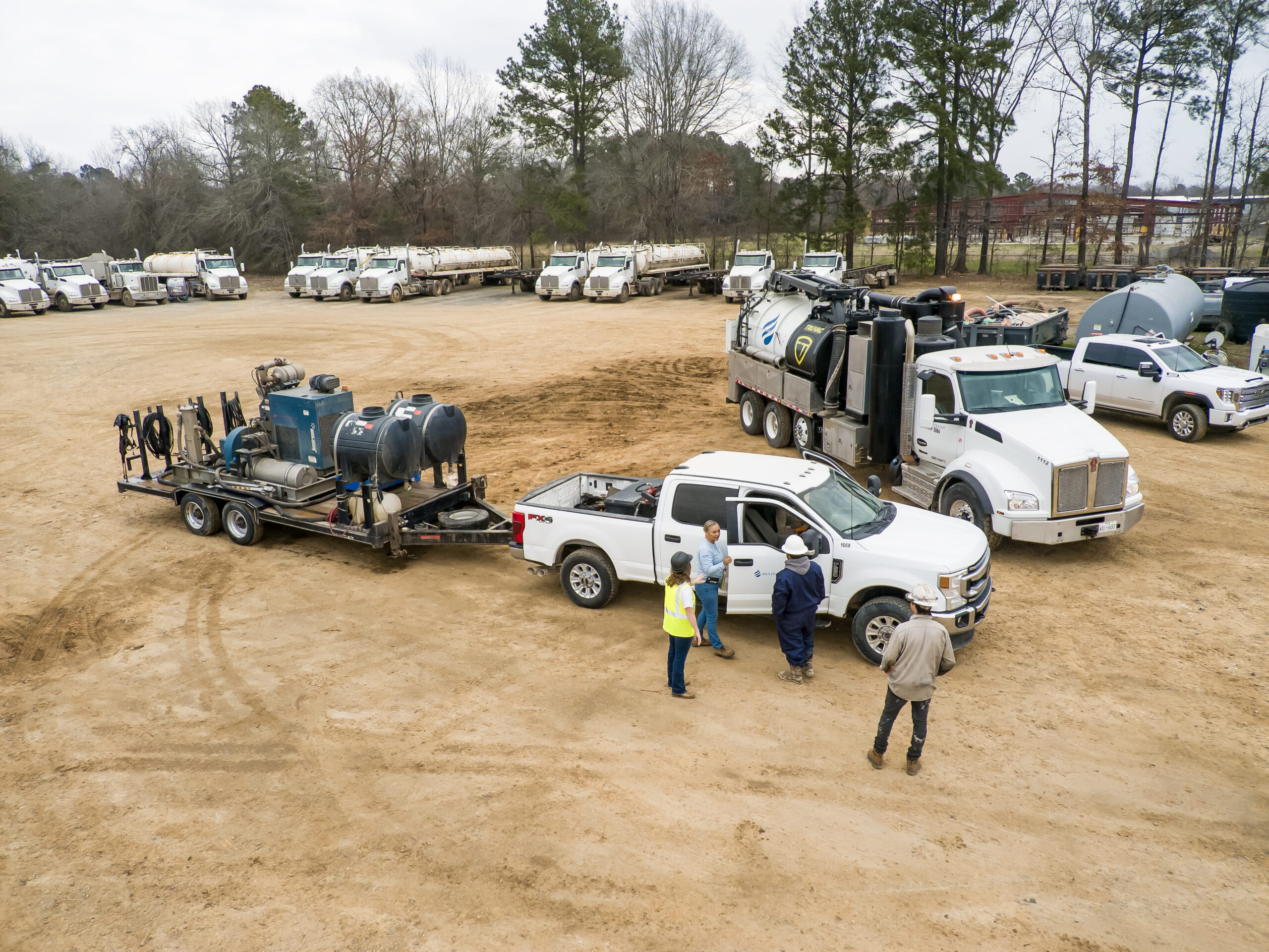 Three men are standing around a truck with a trailer.