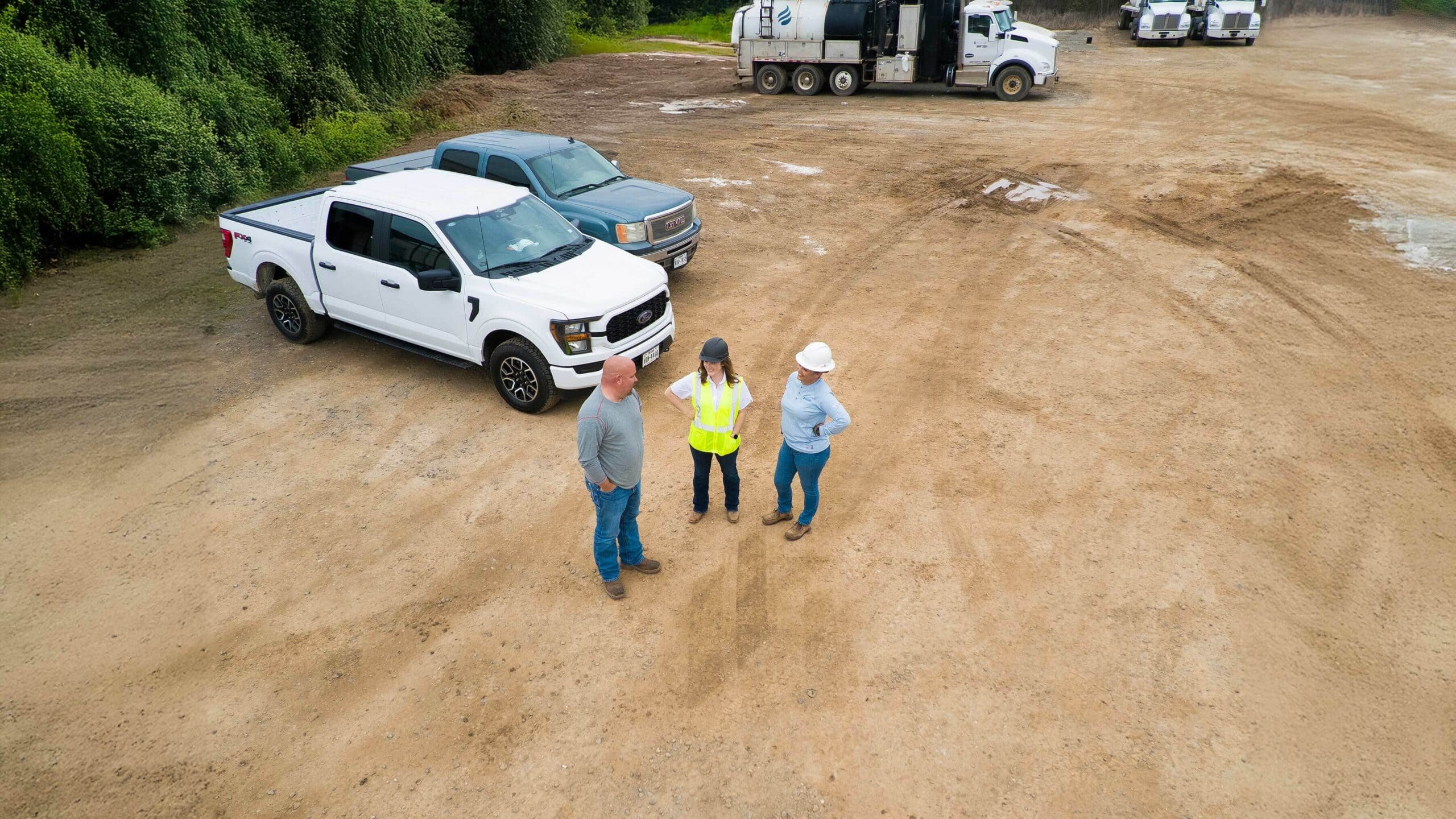 Three people standing in front of a truck and a truck.
